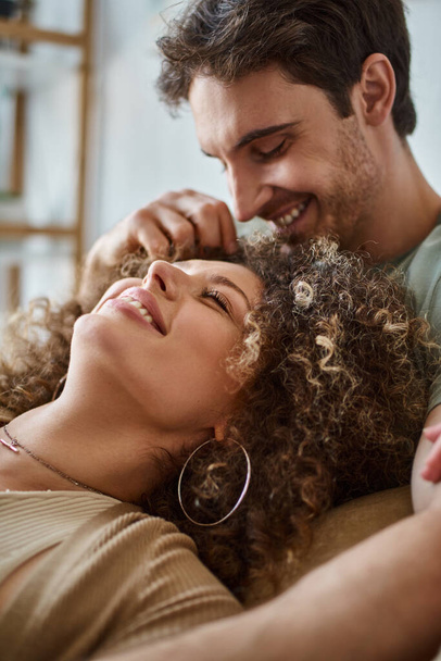 Closeup of curly young woman lying with her boyfriend smiling and laughing together - Foto, afbeelding