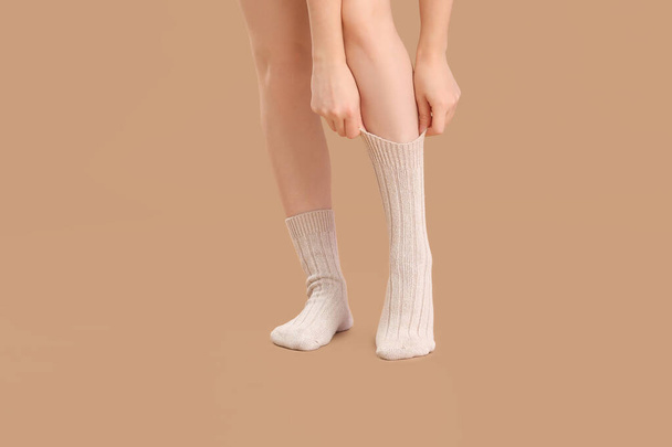 Bej arka planda örgü çoraplı genç bir kadının bacakları. - Fotoğraf, Görsel