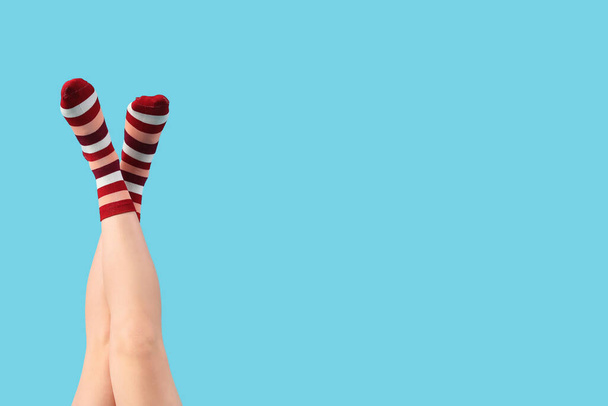 Legs of young woman in striped socks on blue background - Photo, Image