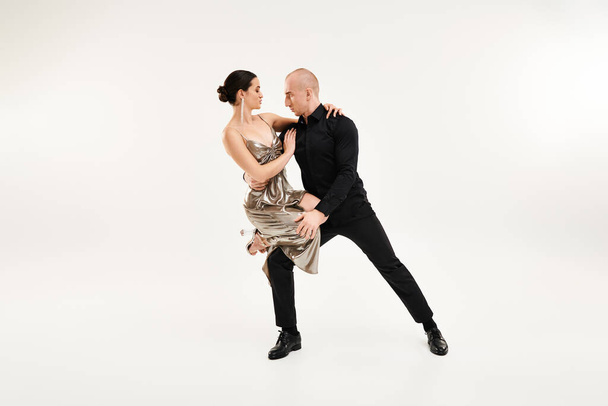 Молодой человек и женщина акробатически танцуют вместе в идеальной синхронизации на белом фоне студии. - Фото, изображение