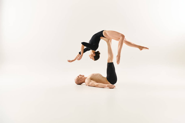 Mladý muž bez trička a žena předvádějící akrobatické dovednosti ve studiu. - Fotografie, Obrázek