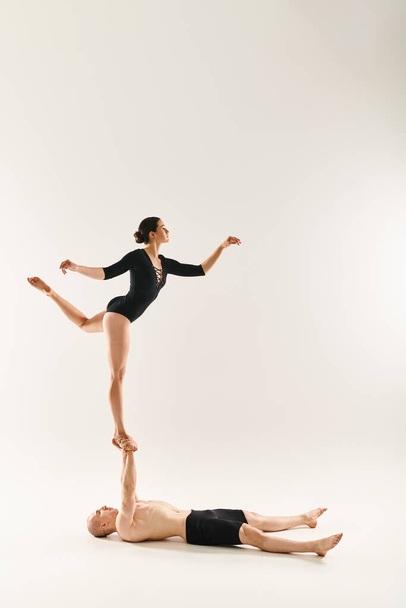白い背景に設定されたスタジオで重力を擁するアクロバティックデュオで踊るシャツレスの若い男女. - 写真・画像