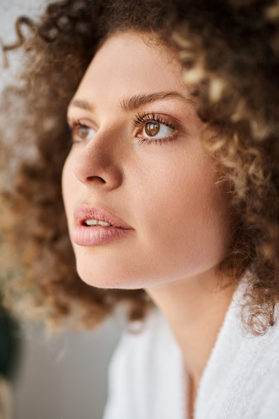 Retrato de close-up de encaracolado bela jovem vestindo roupão branco e olhando para longe - Foto, Imagem