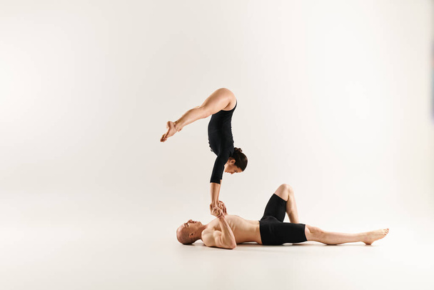 Paidaton mies tasapainottelee toisen miehen kanssa, esittelee voimaa ja taitoa akrobatiassa, valkoisen studion taustalla. - Valokuva, kuva