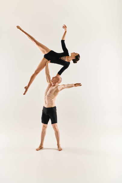 Een shirtloze jonge man en een jonge vrouw dansen in de lucht, acrobatische elementen vertonend in een studio tegen een witte achtergrond. - Foto, afbeelding