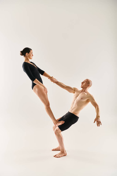 Młody mężczyzna bez koszulki i młoda kobieta tańczą akrobatycznie, zdając się przeciwstawiać grawitacji na białym tle studia. - Zdjęcie, obraz
