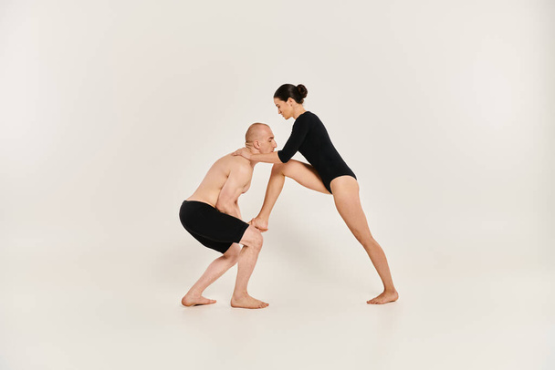 Un giovane uomo senza maglietta e una giovane donna danzano in coppia, eseguendo elementi acrobatici in uno studio girato su sfondo bianco. - Foto, immagini