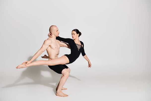 Un joven sin camisa y una mujer en pareja realizando movimientos de danza elegantes y acrobáticos en un ambiente de estudio sobre un fondo blanco. - Foto, Imagen