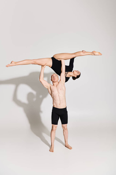 Jovem sem camisa e mulher se envolvem em acrobacias de suporte de mão sincronizadas, mostrando equilíbrio e força. - Foto, Imagem