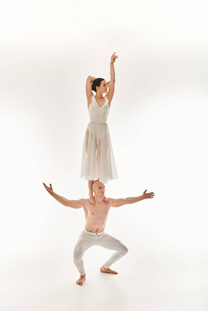 Shirtless young man and woman in white dress display acrobatic dance moves, studio shot. - Photo, Image