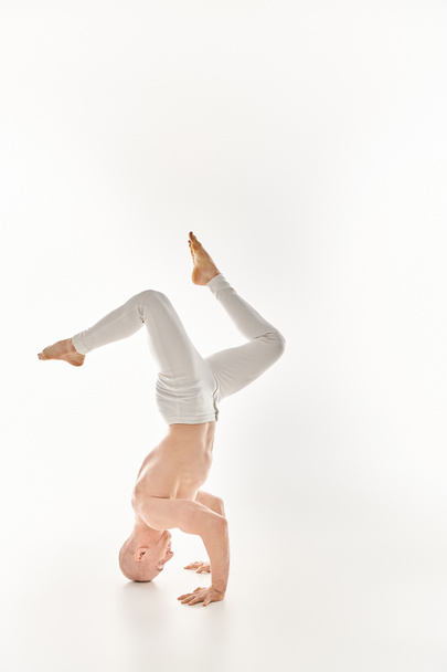 Een man toont kracht en flexibiliteit door het uitvoeren van een headstand. - Foto, afbeelding