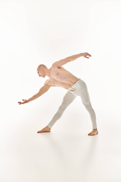 Egy fiatal férfi precizitással és folyékonyan mutatja be az akrobatikus táncmozdulatokat egy stúdióban, fehér háttérrel. - Fotó, kép