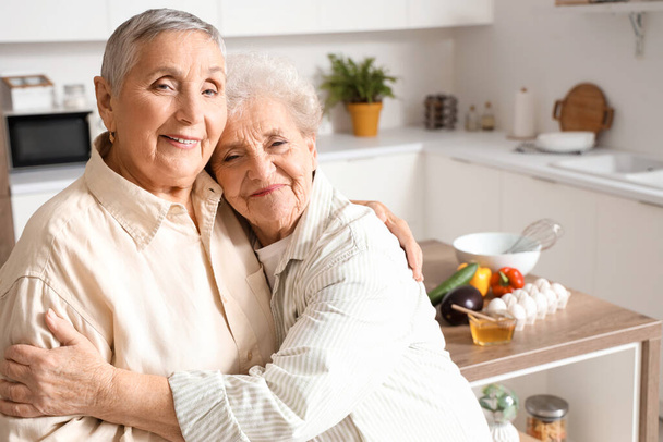 Senior femmes amies câlins dans la cuisine, gros plan - Photo, image