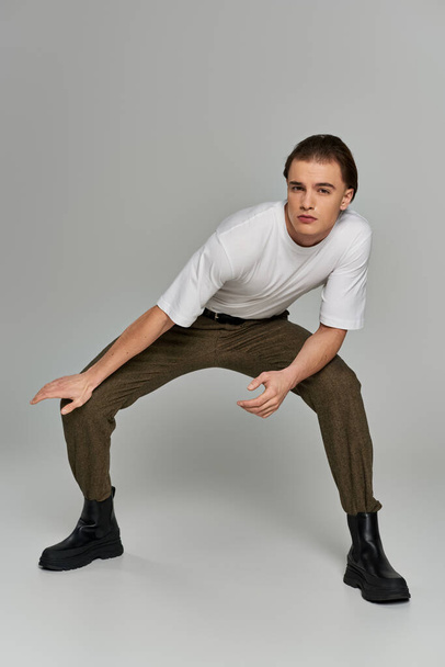 appealing sophisticated man in elegant attire with brown pants posing and looking at camera - Photo, Image