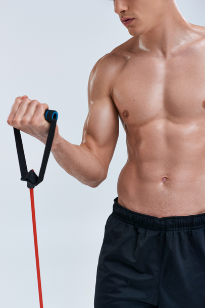 kivágott kilátás fiatal atlétikai ing nélküli férfi edzés fitness expander szürke háttér - Fotó, kép