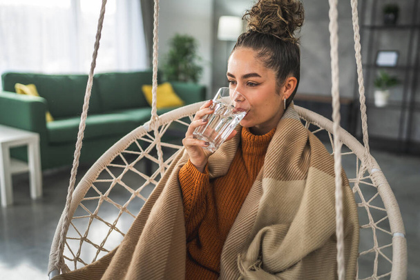 una donna bella giovane donna sedersi a casa con un bicchiere d'acqua - Foto, immagini