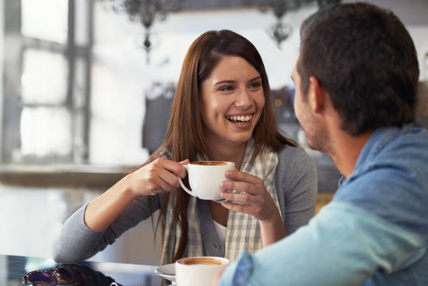 Amore, sorriso e coppia che bevono caffè al caffè, cura e legame insieme il giorno di San Valentino. Uomo felice, donna nel ristorante e tè per connessione, conversazione e rapporto sano nel negozio. - Foto, immagini