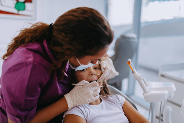 Весела дівчина проходить огляд в сучасній клініці дитячої стоматології.  - Фото, зображення