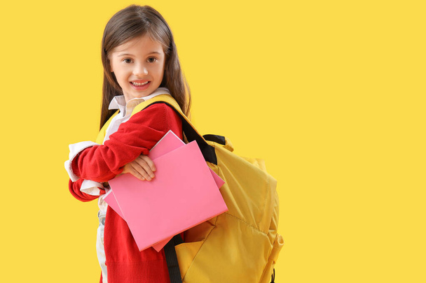 Söpö pieni koulutyttö kanssa copybooks keltaisella taustalla - Valokuva, kuva