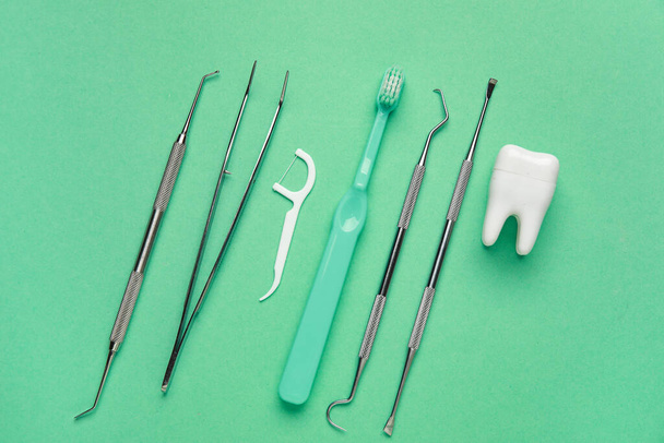 Зубные инструменты и зубная щетка на зеленом фоне. Всемирный день дантиста - Фото, изображение