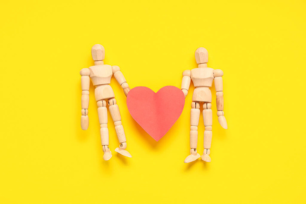 Manequins de madeira com coração de papel sobre fundo amarelo. Celebração do dia dos namorados - Foto, Imagem