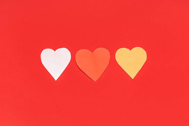 Паперові серця на червоному тлі. Святкування Дня святого Валентина - Фото, зображення