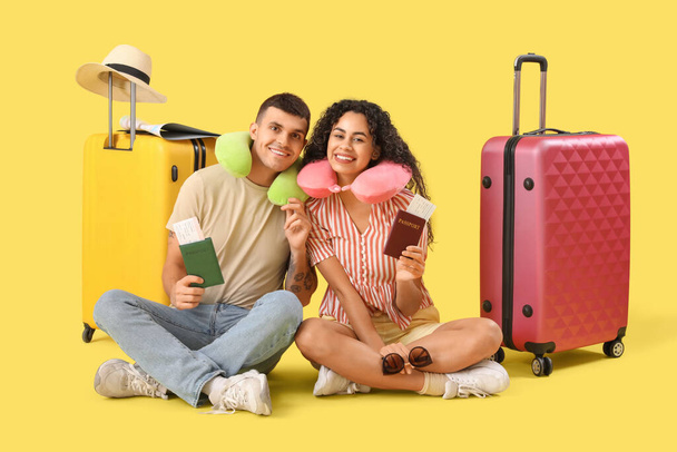 黄色の背景にスーツケースやパスポートを持つ観光客のカップル - 写真・画像