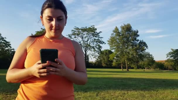 Video von Kaukasierin, die mit Laptop glücklich im Park liegt und leichte Fitness-Kleidung trägt - Filmmaterial, Video