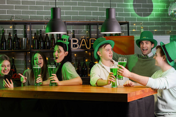Groupe de jeunes avec bière célébrant la Saint-Patrick au comptoir dans un pub - Photo, image