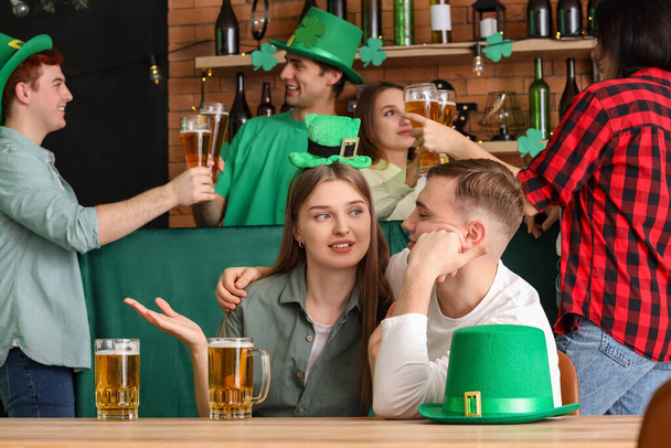 Junges Paar mit Bier feiert St. Patrick 's Day am Tisch in Kneipe - Foto, Bild