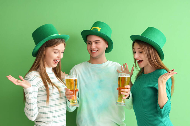 Mladí lidé s pivem na zeleném pozadí. Oslava svatého Patrika - Fotografie, Obrázek