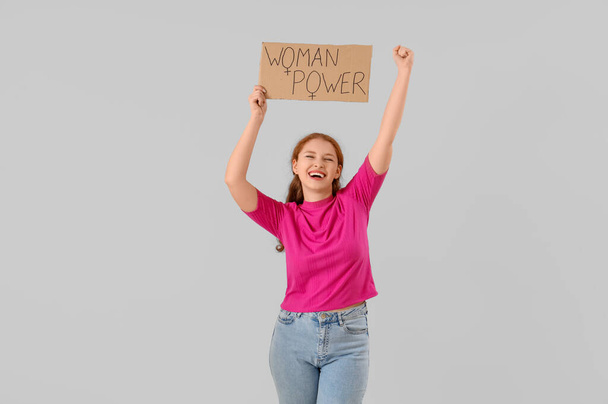 Молодая девушка держит в руках бумагу с текстом Женщина Сила на светлом фоне - Фото, изображение
