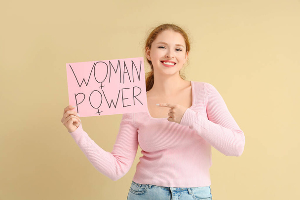 Young girl holding paper with text WOMAN POWER on beige background - Photo, Image