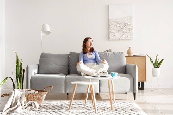 Giovane donna seduta sul divano grigio a casa - Foto, immagini