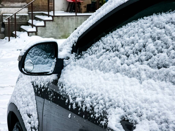 Κοντινό πλάνο πλευρικού καθρέφτη σύγχρονου αυτοκινήτου καλυμμένου με χιόνι - Φωτογραφία, εικόνα
