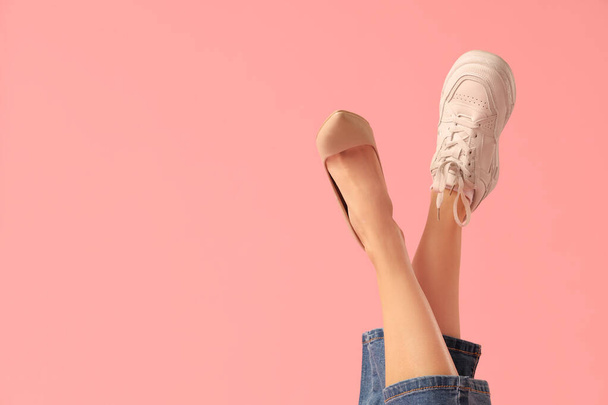 Patas femeninas con zapatilla y zapato sobre fondo rosa. concepto de zapatos incómodos - Foto, Imagen