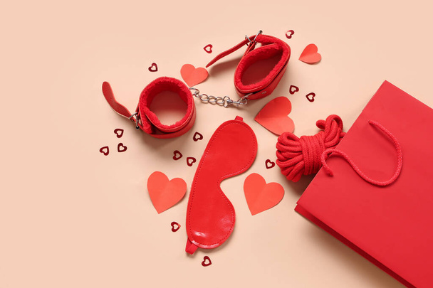 Σύνθεση με τσάντα για ψώνια, ερωτικά παιχνίδια και καρδιές σε φόντο χρώματος. Γιορτή του Αγίου Βαλεντίνου - Φωτογραφία, εικόνα