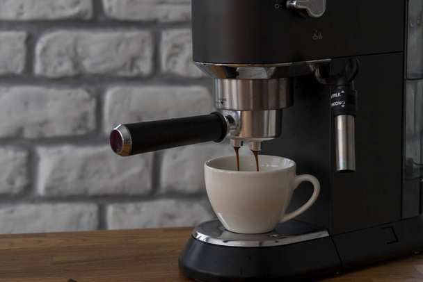 A kávéfőző megtölt egy poharat expresso-val. Italt reggelire.. - Fotó, kép