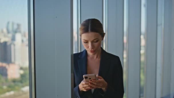 Κομψό businesswoman μηνυμάτων κινητό τηλέφωνο σε απευθείας σύνδεση στο σύγχρονο γραφείο closeup. Dreamy οικονομικός διευθυντής λαμβάνοντας διάλειμμα πληκτρολογώντας smartphone σε πανοραμική παράθυρο. Διοικητικό στέλεχος εταιρείας που αναπαύεται κύλιση κυττάρων. - Πλάνα, βίντεο