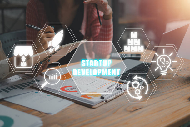 Startup-Entwicklungskonzept, Business-Team analysiert Einkommensdiagramme und Diagramme auf dem Schreibtisch mit Startup-Entwicklungssymbol auf virtuellem Bildschirm. - Foto, Bild
