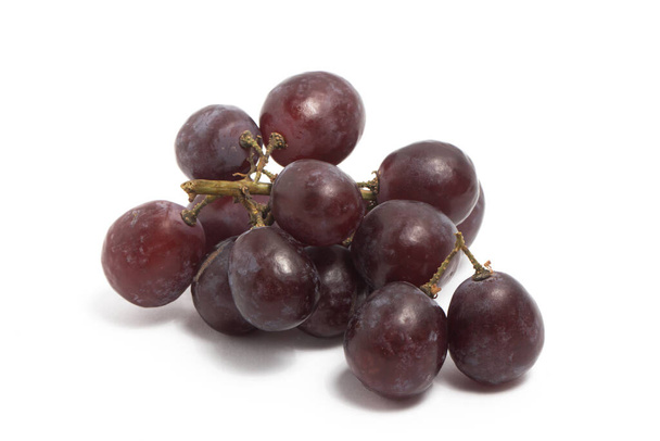 Un pequeño ramo de uvas rojas orgánicas frescas deliciosa fruta aislada en el camino de recorte de fondo blanco - Foto, imagen