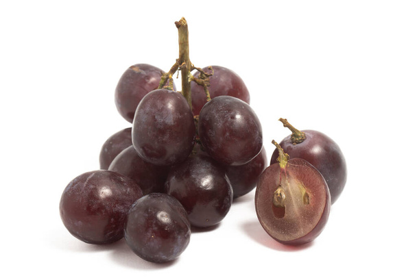 Un pequeño racimo y rebanadas de uvas rojas orgánicas frescas deliciosa fruta aislada en el camino de recorte de fondo blanco - Foto, imagen