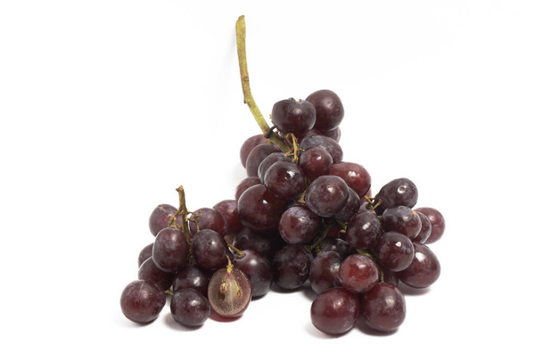 Cortado en rodajas y un ramo de uvas rojas orgánicas frescas deliciosa fruta aislada en el camino de recorte de fondo blanco - Foto, imagen