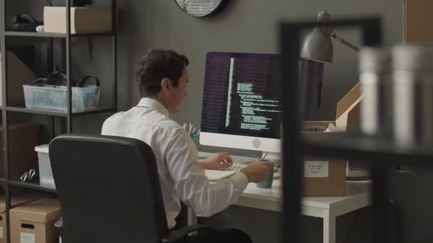 Зворотній перегляд середній знімок молодого інженера-програміста, який пише складний код програми html на чорному дисплеї комп'ютера під час роботи в агентстві кібербезпеки - Кадри, відео