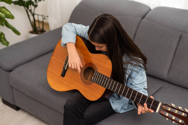 Портрет усміхненого студента-підлітка, який практикує гітару під час уроків музики. Високоякісна фотографія - Фото, зображення