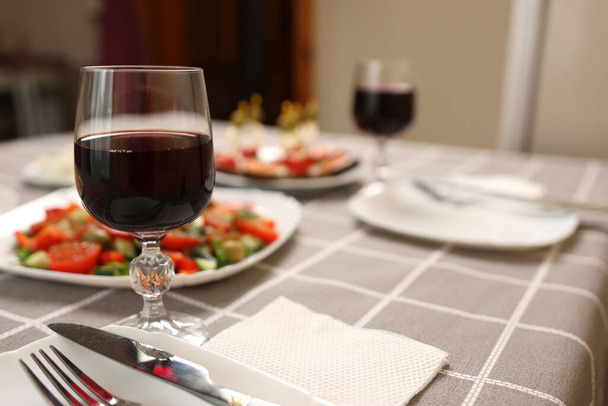 Красное вино наливают в бокал на стол с праздничными блюдами - Фото, изображение