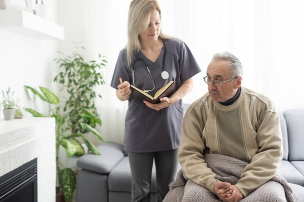 Kind female doctor embracing encouraging senior male patient in hospital. Happy healthy older man and his physician enjoying talking at nursing home. Elderly medical health care concept - Photo, Image