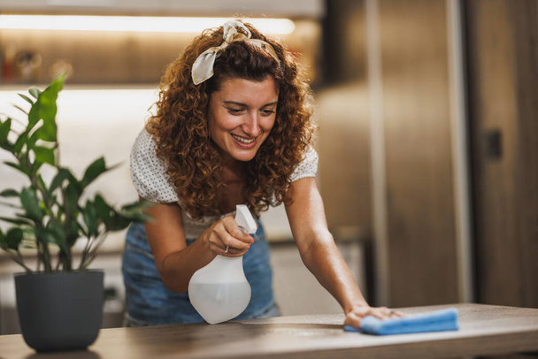 Krásná usmívající se žena čištění a otírání domů s látkou a sprejem pro hygienu bakterií a prachu. - Fotografie, Obrázek