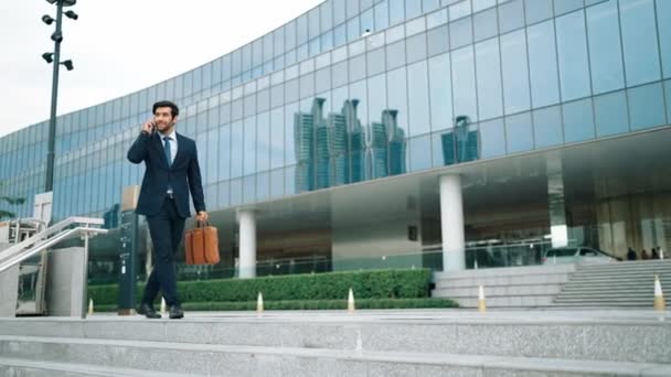 Smart business man using phone to talking while walking at building. Happy manager walking at street while talking on smart phone to discuss business plan or marketing strategy or working. Exultant. - Footage, Video