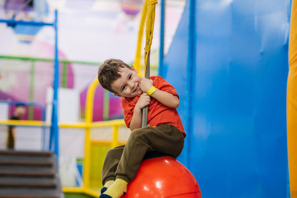 Egy vidám kisfiú játszik a játszótéren a gyermek szórakoztató központban. - Fotó, kép